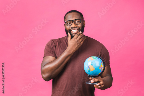 Cheerful african american black man holding the globe with love and care isolated over pink background. Travel concept  looking for a jorney.