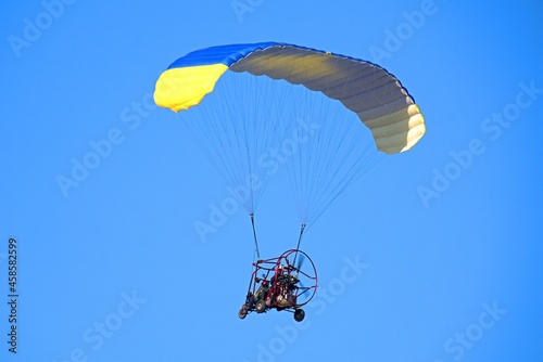 Yellow-blue paraglider in the blue sky