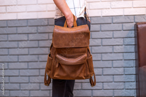 Man holding brown leather backpack in the hand