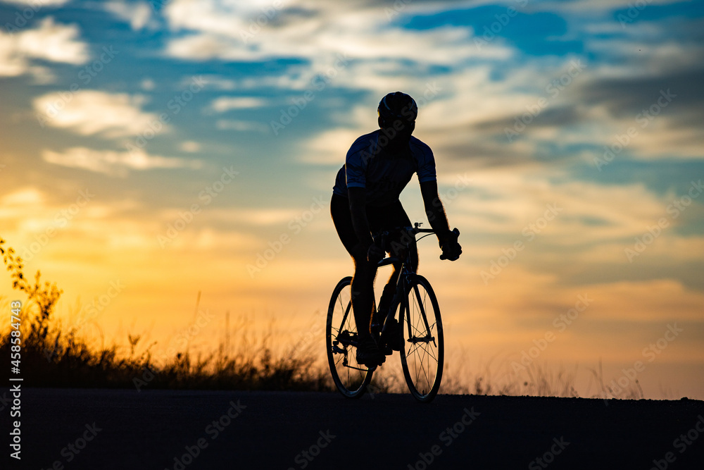 Obraz premium cyclist silhouette at sunset sports and fitness concept