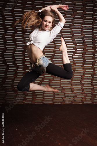 Gymnast's jump in the gym. A girl with a flexible figure.