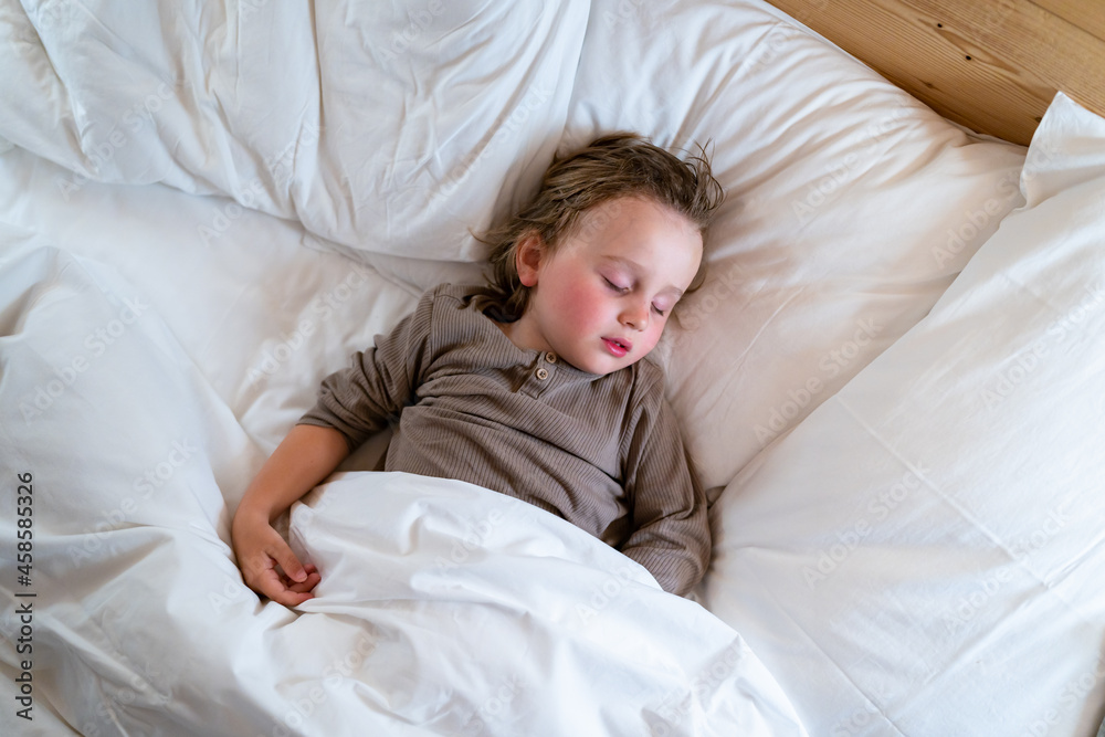 Little preschool boy wearing pajamas is sleeping in the bed at home. Child doesn't want to wake up in the morning. Little preschool boy wearing pajamas is sleeping in the bed at home. Child doesn't want to wake up in the morning.