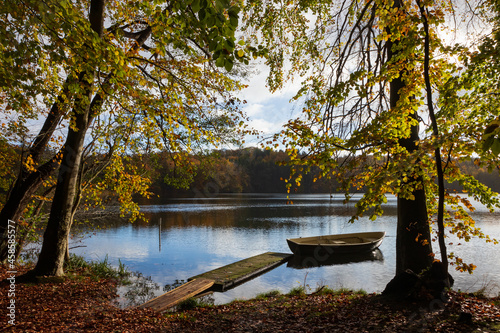 Idyllic lake scenery with rowboat and jetty in beautiful fall colors.