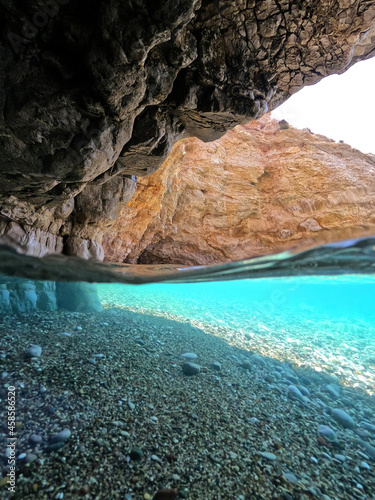 Underwater split photo of beautiful paradise pebble rocky bay of Kaladi with turquoise crystal clear sea and small caves, Kithira island, Ionian, Greece © aerial-drone