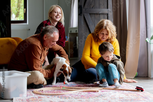 grandparents play the railway with their grandson at home.