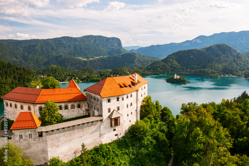 Aerial view of mediaeval Bled castle on the cliff of the mountain under lake Bled with turquoise blue water in Slovenia