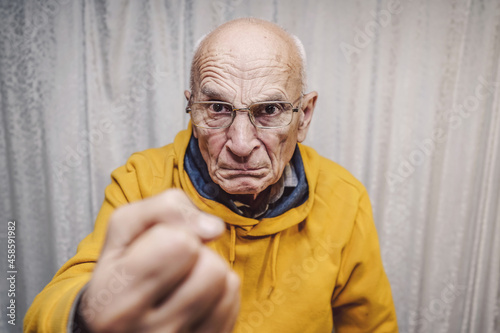 Canvas Print Portrait of angry caucasian man wearing eyeglasses and showing fist