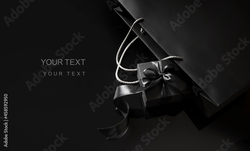 Black Friday background. Elegant black gift box with a black bow ribbon near the black package. Black Friday sale template with a copy space.