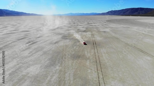 Riding movement of red sport car in death valley with salt flats ground of Bonneville lake, travel time for exploring desolate area of nature in America with wild route track for drifting
 photo