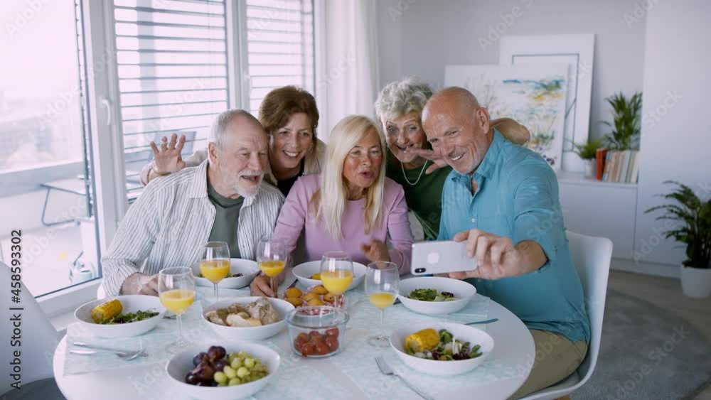 Group of senior friends having party indoors, taking selfie when eating at the table. Group of senior friends having party indoors, taking selfie when eating at the table.