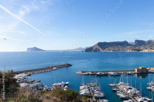 Coastline of the Mediterranean resort of Calpe, Spain with sea and yachts, lake, skyscrapers and mountain range.