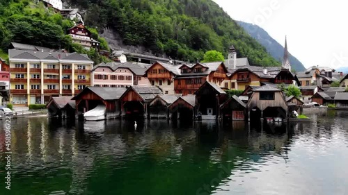 Zoom out from wharf moorage with water boat for rent and exploring picturesque nature environment on vacation, drone view on architecture buildings in Austrian city Hallstatt
 photo