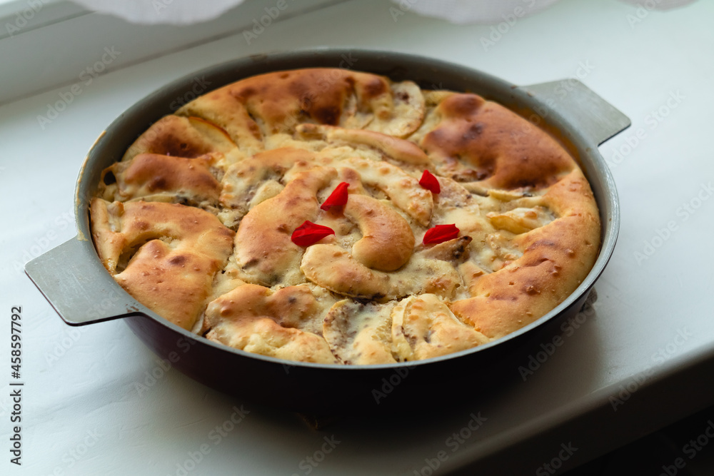 Autumn round apple pie with cinnamon with a golden crust on a light table.