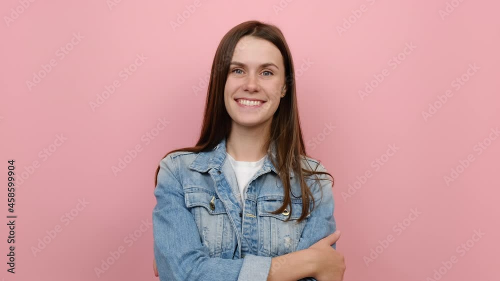 Portrait of smiling fun young caucasian woman 20s years old wears denim jacket, happy looking at camera, posing isolated over pastel pink color background wall in studio. People lifestyle concept Portrait of smiling fun young caucasian woman 20s years old wears denim jacket, happy looking at camera, posing isolated over pastel pink color background wall in studio. People lifestyle concept