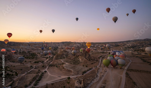 Cappadocia, Turkey: Wide angle aerial panoramic shot of colorful hot air balloons together floating in the sky at early morning sunrise horizon in Goreme national park