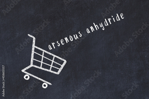 Chalk drawing of shopping cart and word arsenous anhydride on black chalboard. Concept of globalization and mass consuming photo