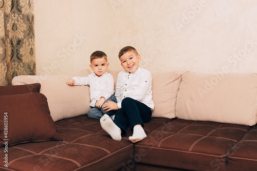 Fotografie Two little brothers in white shirts sitting on the couch