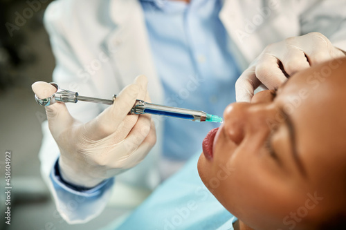 Close-up of black woman receiving anesthetic during dental procedure at dentist s office.