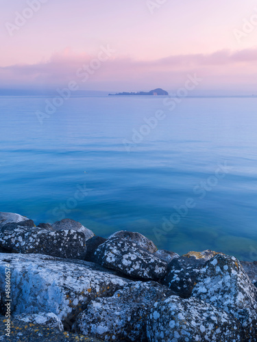 view to island Bisentina from stones in blue morning on lake Bolsena in Italy