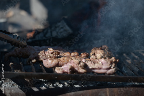 Argentine chinchulines cooking on the coals on a steaming grill photo