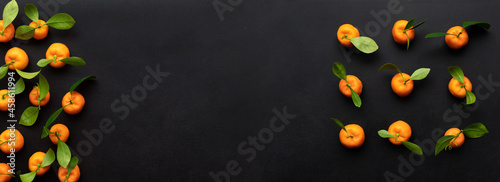 Clementines with leaves on a black background. Top view with copy space.