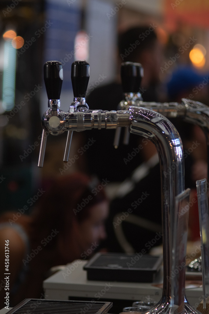 Beer taps closeup at the craft beer festival in Ukraine, the city of Lviv. Vertical photo, blurred background.