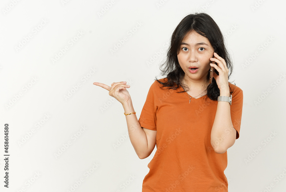 Talking on the phone and pointing side of beautiful asian woman Wearing orange T-shirt isolated on white background Talking on the phone and pointing side of beautiful asian woman Wearing orange T-shirt isolated on white background