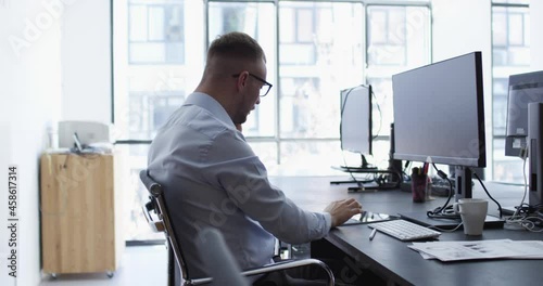 Side view of Caucasian graphic designer using electronic stylus for creating project calling to business partner for discussing ideas, formally dressed IT professional checking touch pad notifications