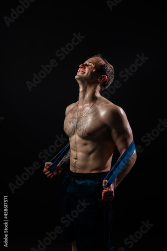 Man on black background keeps dumbbells pumped up in fitness bodybuilding chest training workout hold heavy, shirtless pectoral. Young handsome people fit With a ribbon in hand, the fitness gum is
