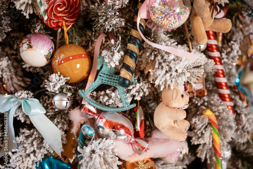 a fragment of a decorated Christmas tree with colorful colorful toys, taken close-up in the living room. The concept of relaxation and home comfort.