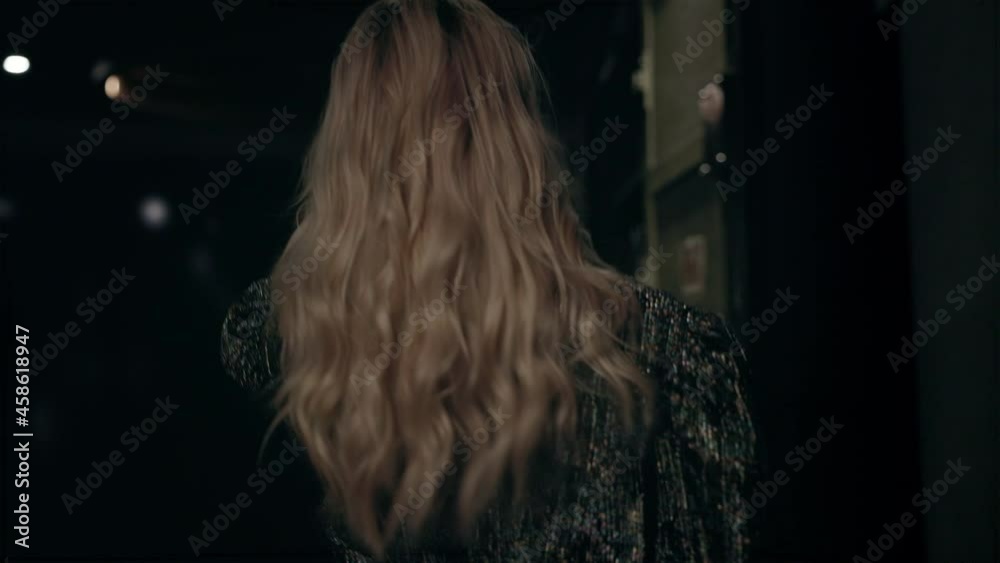 Stylish Blonde With Long Hair Runs In Hotel. She Is Holding Shoes In Her Hands. Rear View. Stylish Blonde With Long Hair Runs In Hotel. She Is Holding Shoes In Her Hands. Rear View.