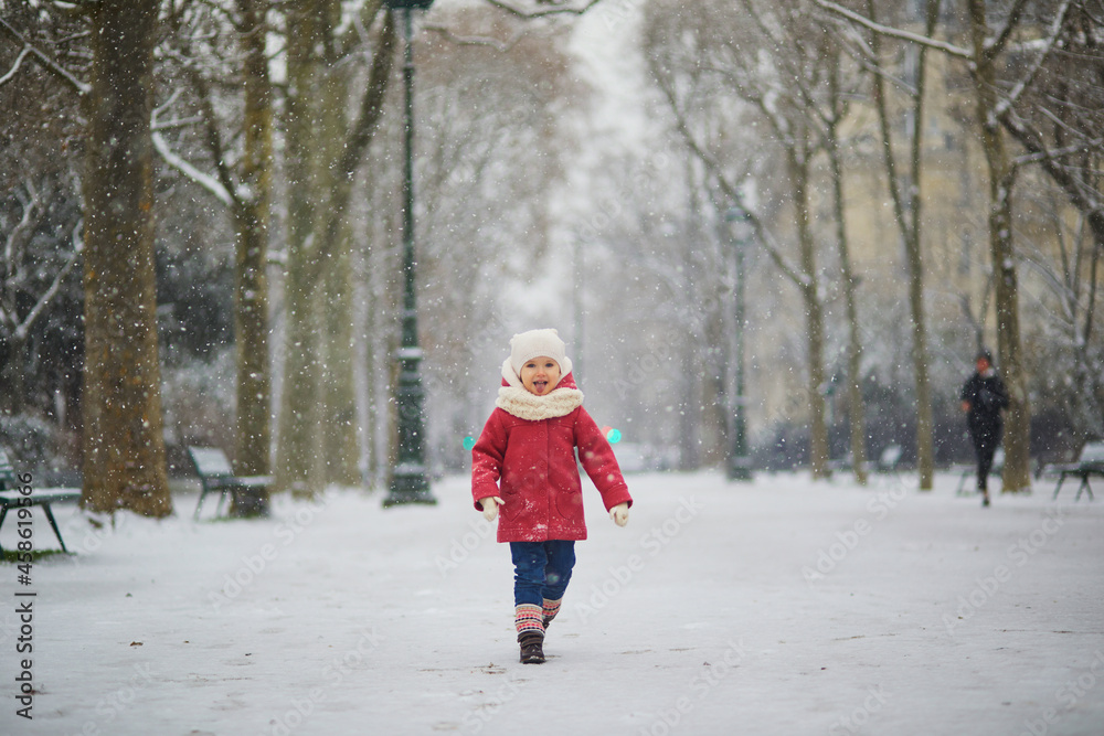 Adorable toddler girl on a day with heavy snowfall