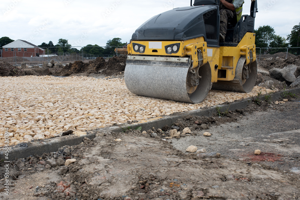 Drum Ride On Roller compacting freshly laid tarmac during roadworks and new footpath construction Drum Ride On Roller compacting freshly laid tarmac during roadworks and new footpath construction
