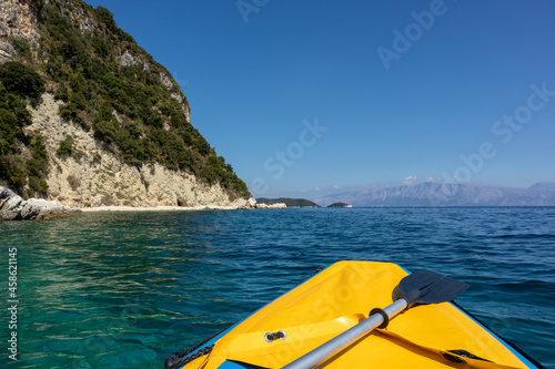 Yellow boat and paddle on blue clear calm Ionian Sea bay, view from boat. Nice clouds reflection and scenic green rocky cliffs coast. Lefkada island in Greece. Idyllic travel activity © Kathrine Andi