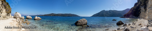 Wide panorama of white pebbles and rocks beach with azure clear water on coast of Lefkada island in Greece. Summer nature travel to Ionian Sea