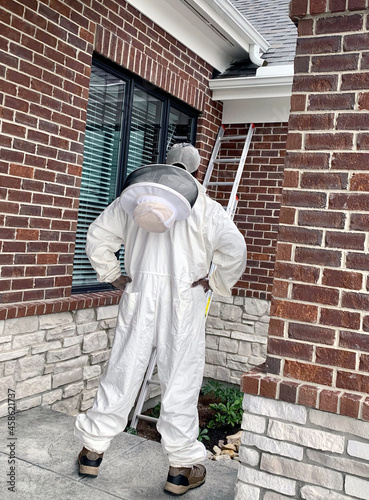 Pest control technician survey bee removal in bee suit