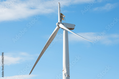 Electricity power wind turbine with broken blade and damaged tower awaiting repair after accident. photo