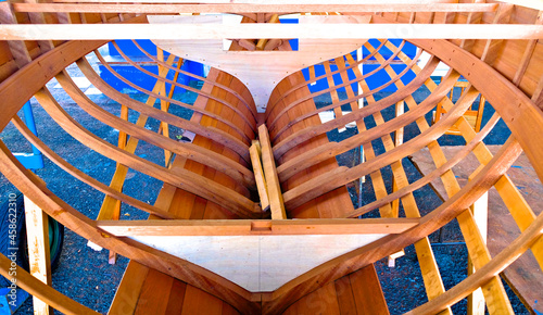 Small wooden boat in boatyard construction. Timber structure with ribs, keel, bulkheads and longitudinal members in place.