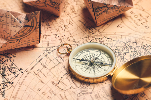 Old compass and paper boats on vintage world map