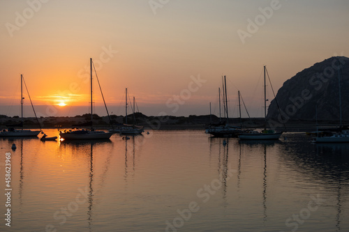 Fototapeta Naklejka Na Ścianę i Meble -  A Colorful Orange Sunset in Morro Bay, California, with Boats and the Morro Rock