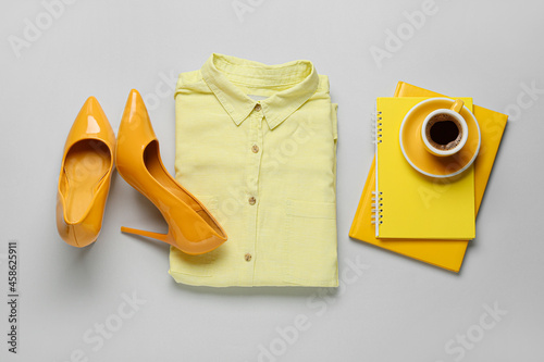 Female clothes, accessories and cup of coffee on light background