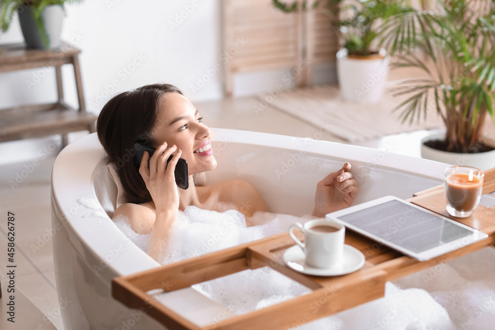 Young woman talking by mobile phone while taking bath at home Young woman talking by mobile phone while taking bath at home