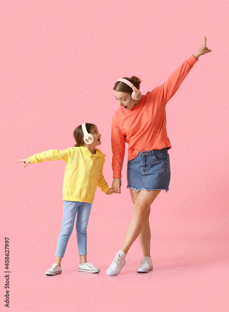 Young woman and her little daughter dancing and listening to music on color background Young woman and her little daughter dancing and listening to music on color background