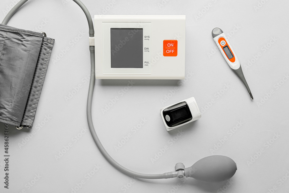 Pulse oximeter with sphygmomanometer and thermometer on light background Pulse oximeter with sphygmomanometer and thermometer on light background