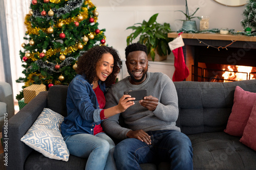 Happy african american couple having video call on smartphone, christmas decorations in background © wavebreak3