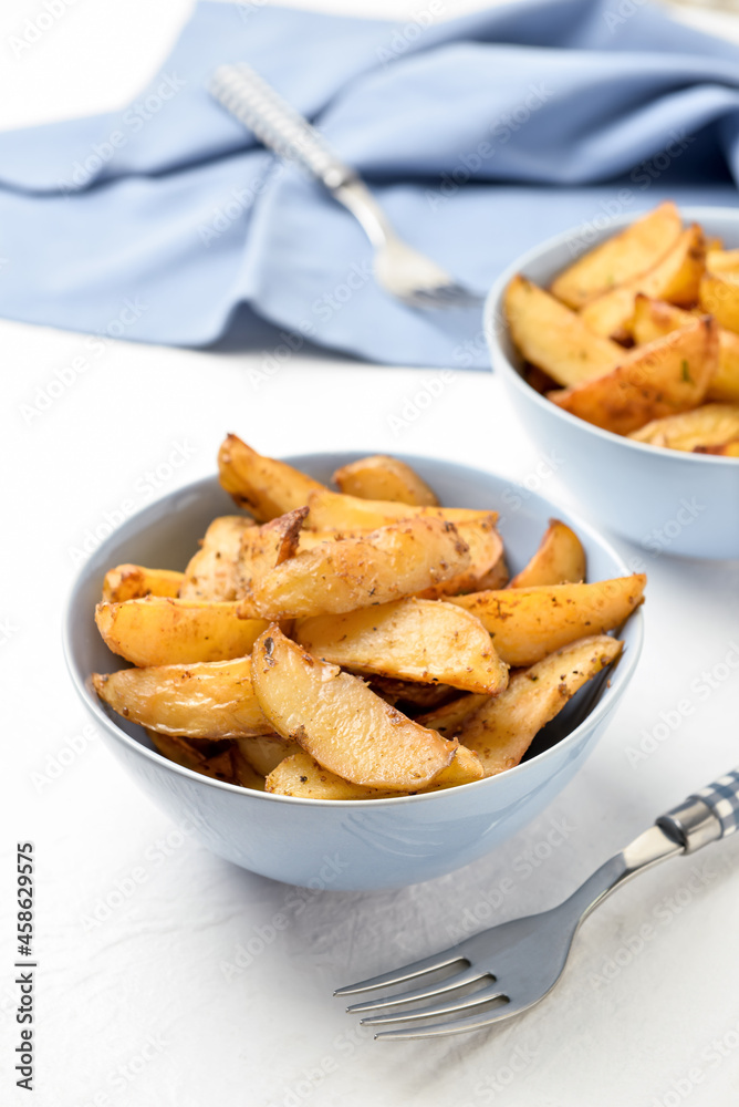 Bowls with tasty baked potato on light background