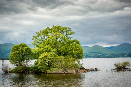 Along the West highland Way in Scotland. A small island on Loch Lomond covered with vegetation and green trees photo