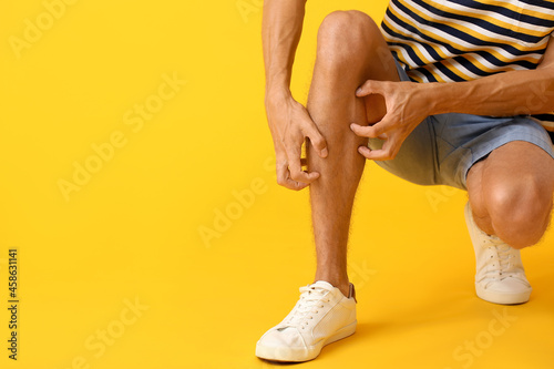 Young man scratching himself on color background