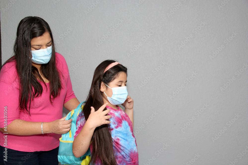 Latina mom and daughter prepare for back to school in the new normal due to the Covid-19 pandemic with backpack and face shield to protect from Coronavirus
