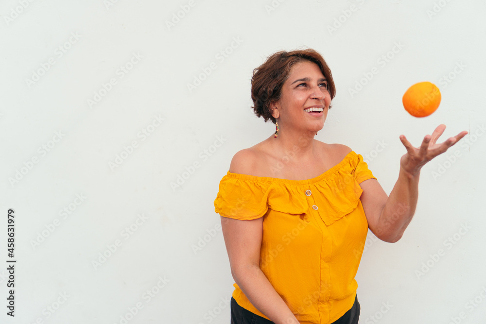Mature woman plays with oranges in the open air